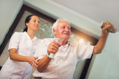 female caregiver assisting senior man in his daily exercise