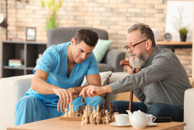 senior man playing chess with his male caregiver